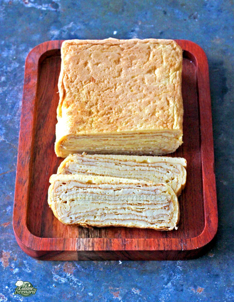 A whole and sliced loaf of crustless white bread on a wooden cutting board.