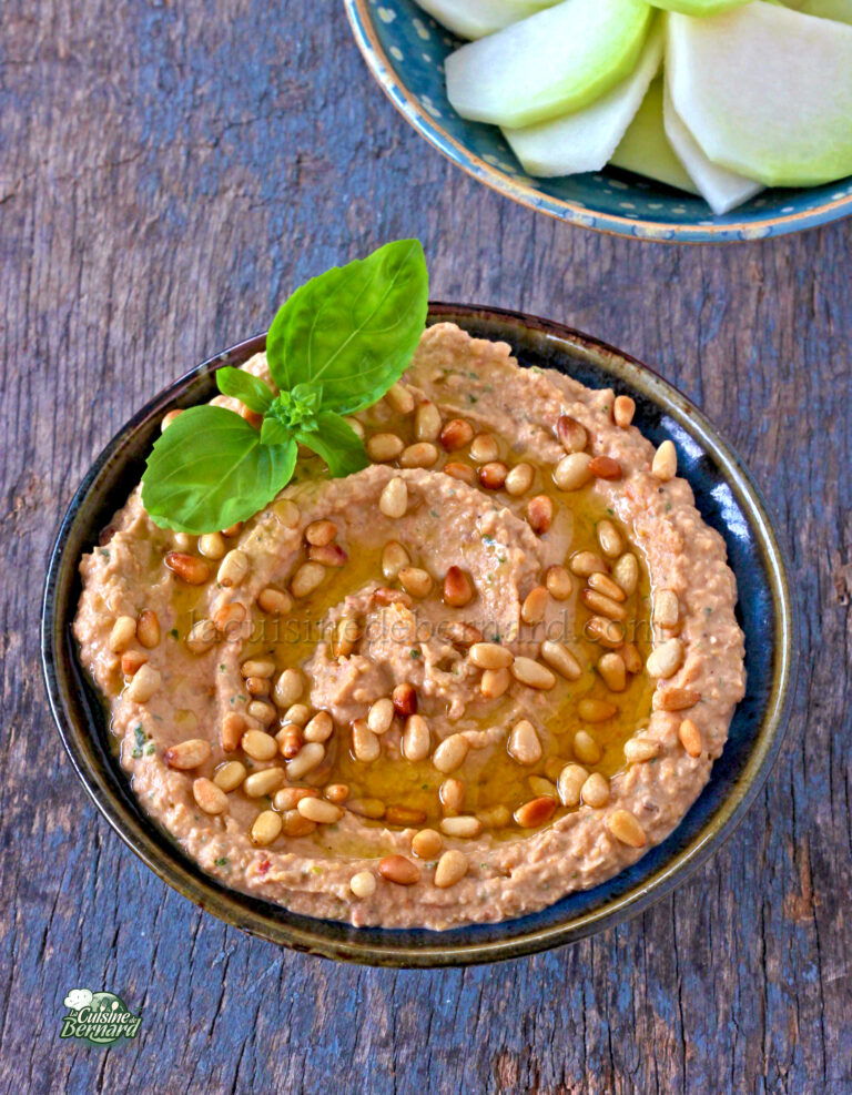 A bowl of hummus and apples on a wooden table.