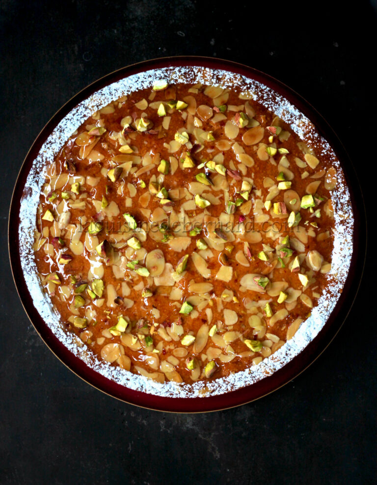 A pie with nuts and pistachios on a plate.