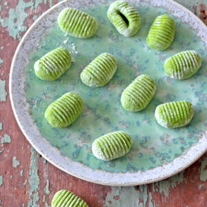 Gnocchis verts sur une assiette sur une table en bois.