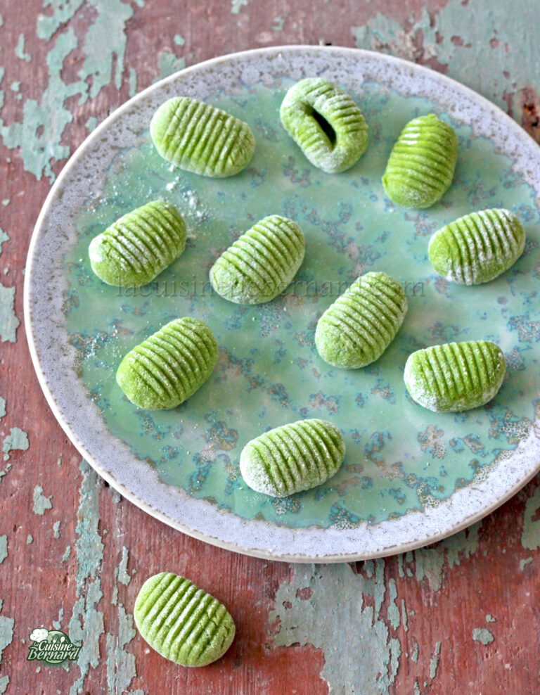 Green gnocchi on a plate on a wooden table.