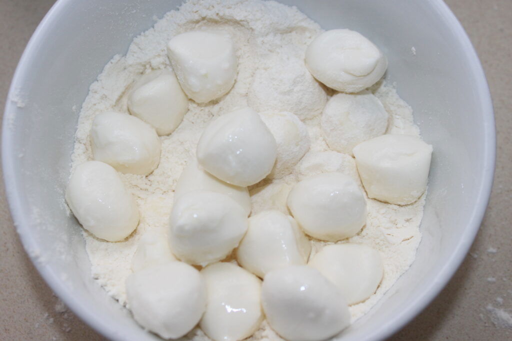 Uma tigela branca com pequenas bolas redondas de queijo Mozza em uma camada de farinha, perfeita para mergulhar na maionese de wasabi.