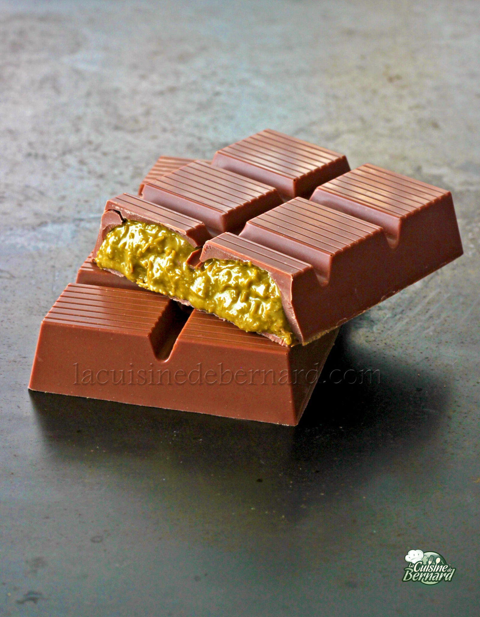 Une barre de chocolat de luxe est cassée en deux, révélant une garniture jaune crémeuse et texturée à l'intérieur un délice gourmand inspiré des saveurs du Chocolat de Dubaï.