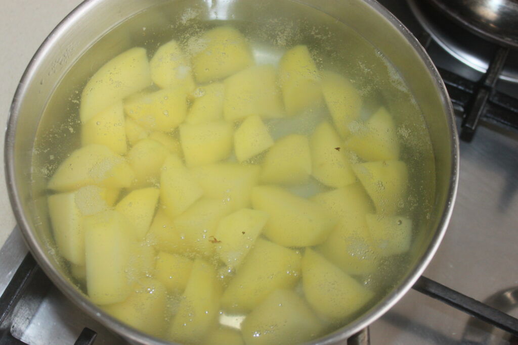 Des pommes de terre coupées en dés mijotant dans une casserole d'eau sur la cuisinière, bientôt transformées en une purée crémeuse, se marient parfaitement avec des petits pains moelleux pour un repas réconfortant par excellence.