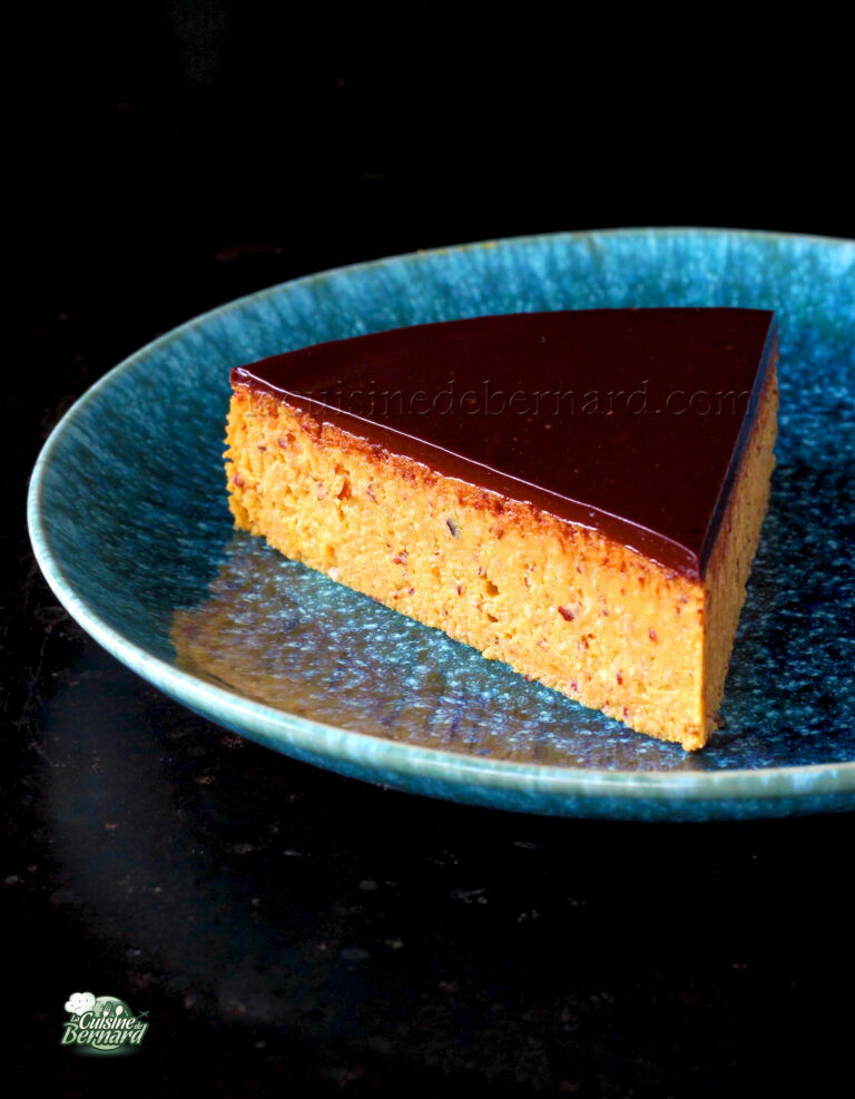 A slice of layered cake with a glossy chocolate topping on a blue plate.